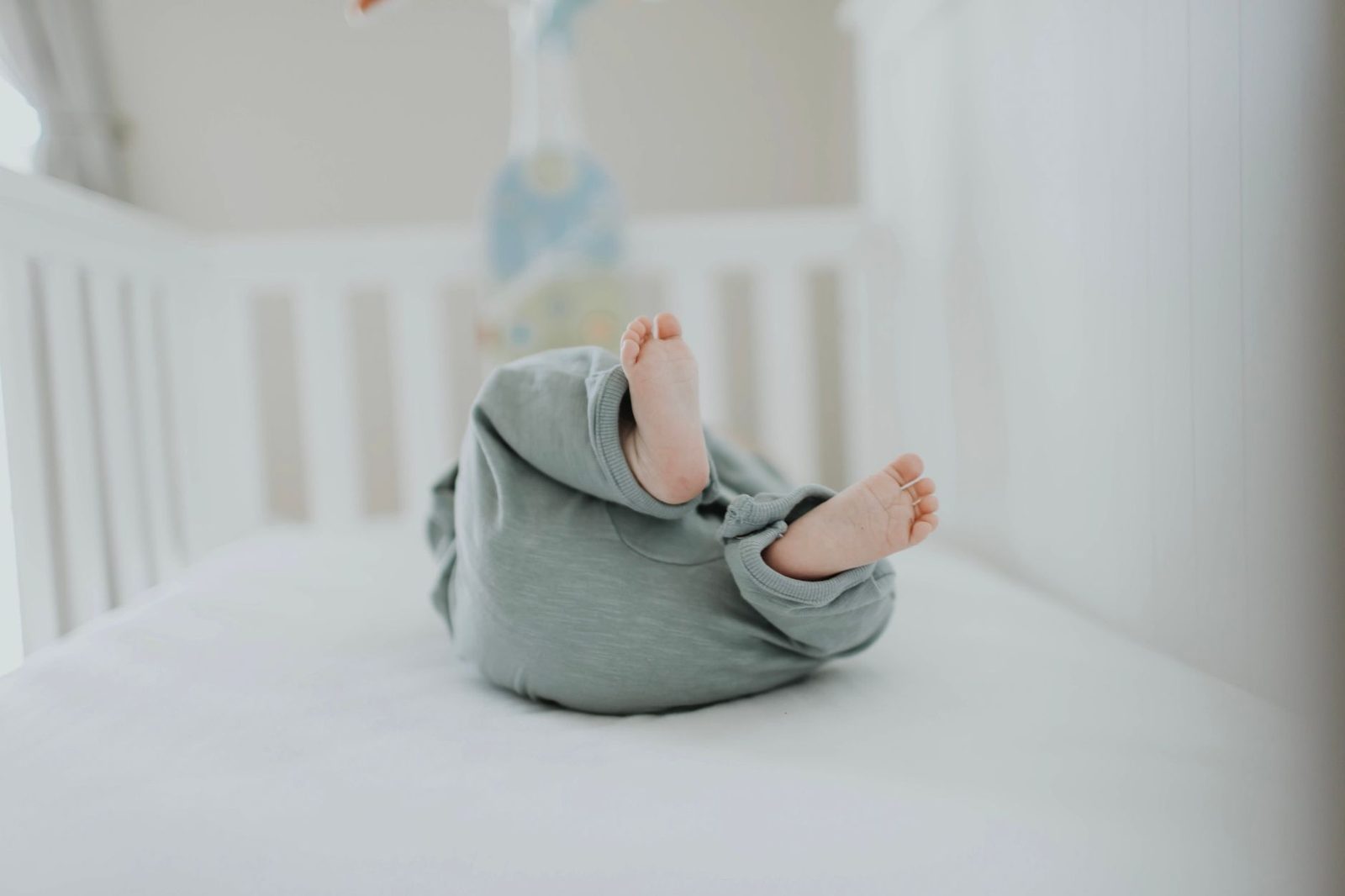 Baby in een pyjama en slaapzak ligt rustig te slapen in het bedje