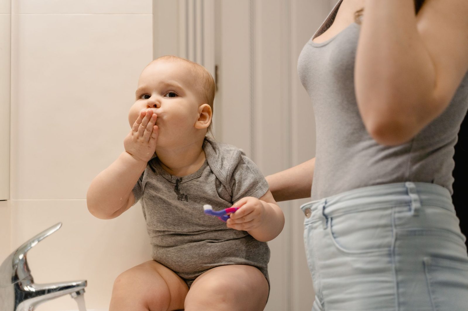 Baby met een tandenborstel in de badkamer, poetsen vanaf het eerste tandje