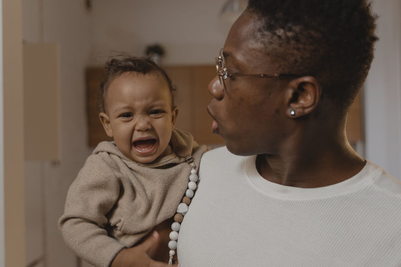 Dragen en nabijheid helpen een baby door een krampjesbui heen Vader draagt en troost zijn huilende baby tijdens een krampjesbui in de avond