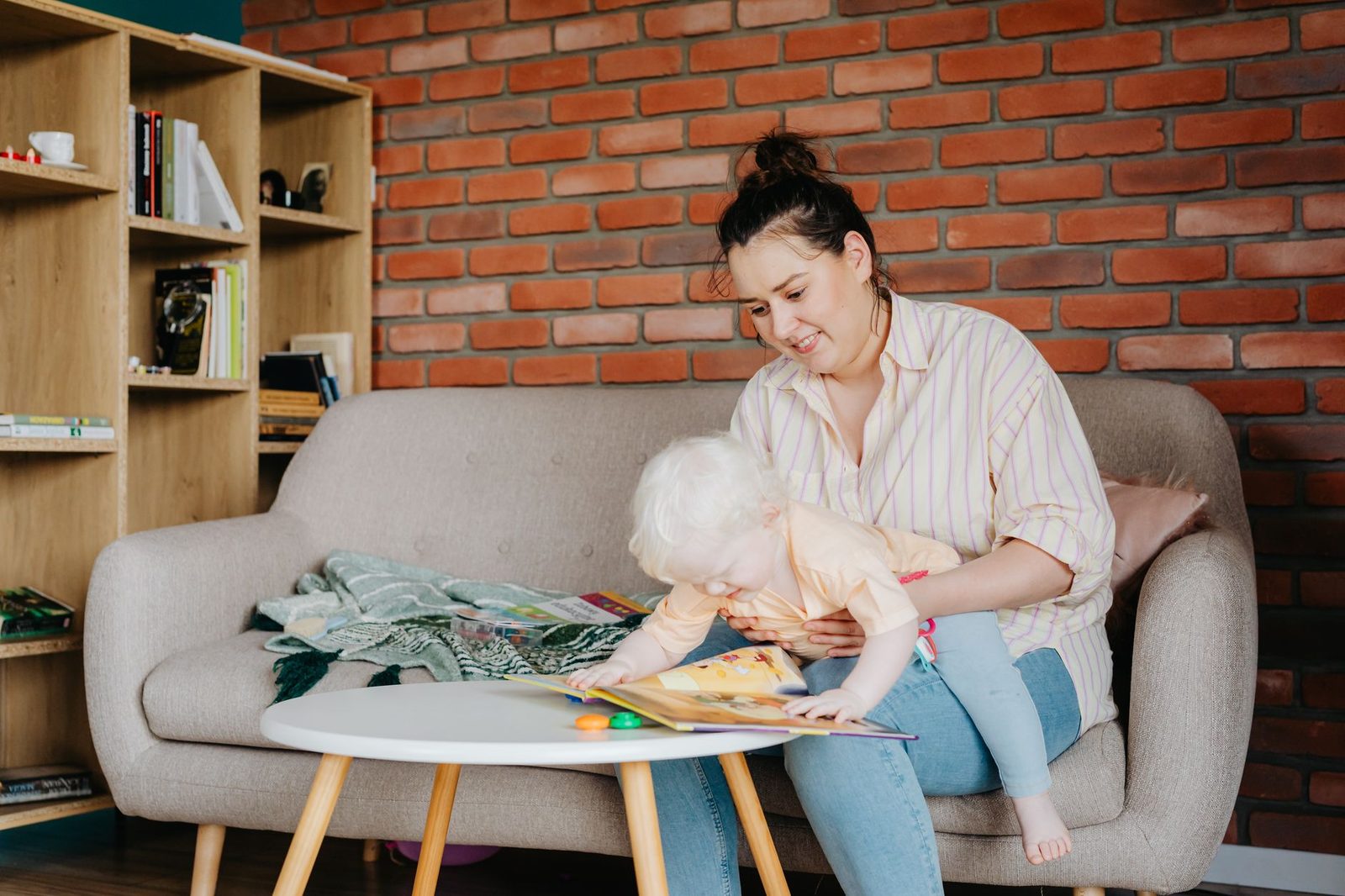 Peuter Place, voor ouders van baby's, peuters en kleuters Ouder leest samen met haar jonge kind een prentenboek op de bank